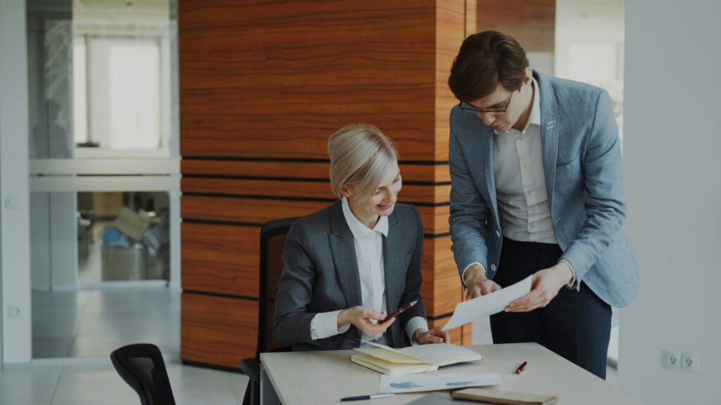 Manager remettant un document à une collaboratrice dans un bureau, symbole de la délégation en entreprise.