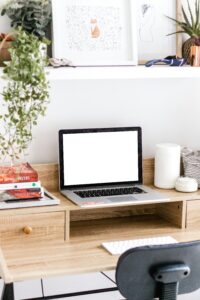 Bureau minimaliste avec ordinateur portable allumé, illustrant la collaboration à distance et l’externalisation pour entreprises et associations.