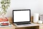 Bureau minimaliste avec ordinateur portable allumé, illustrant la collaboration à distance et l’externalisation pour entreprises et associations.